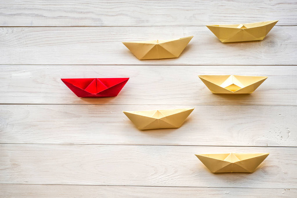 origami papier boten volgen een leider op witte rustieke achtergrond - Foto, afbeelding