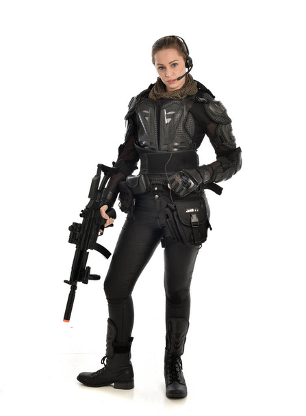 täyspitkä muotokuva naissotilas yllään musta taktinen panssari, pitämällä kivääri ase, eristetty valkoinen studio tausta
. - Valokuva, kuva