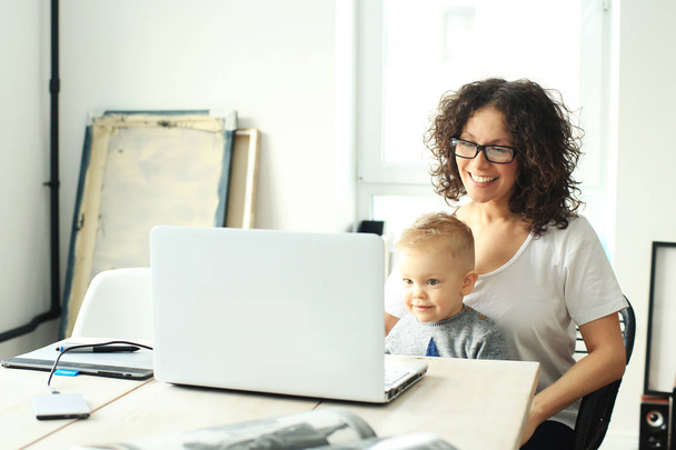 Mother and young son sitting at a table near the laptop - Photo, Image