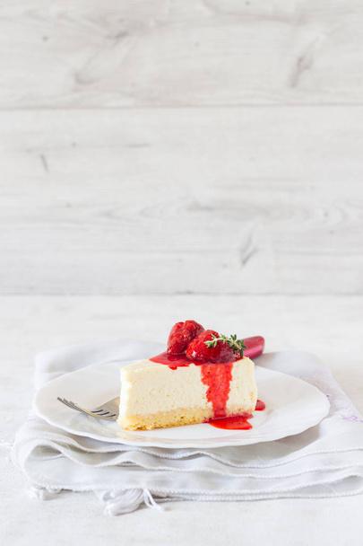 Piece of delicate cheesecake with strawberries sauce on a white plate.  - Φωτογραφία, εικόνα