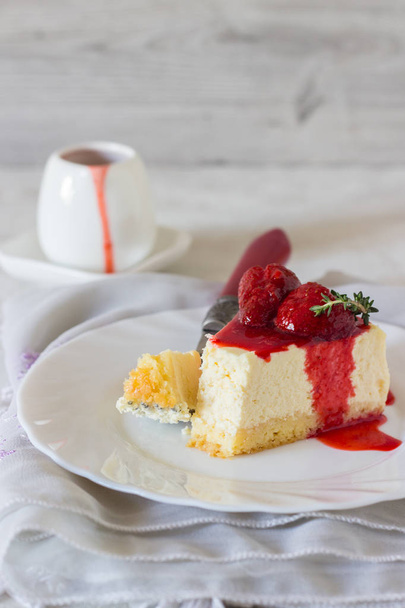 Piece of delicate cheesecake with strawberries sauce on a white plate.  - Φωτογραφία, εικόνα
