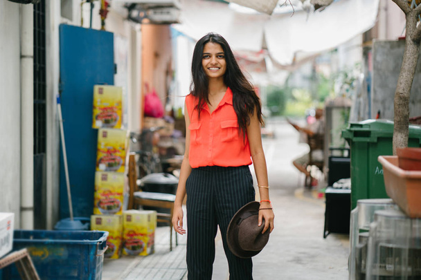 Portrait of a young Indian Asian model  standing in an alley in Asia. She is smiling and looking away in the day, and is elegant, pretty and tall. - Fotó, kép