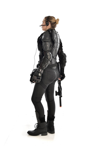 full length portrait of female  soldier wearing black  tactical armour, holding a rifle gun, isolated on white studio background. - Foto, immagini