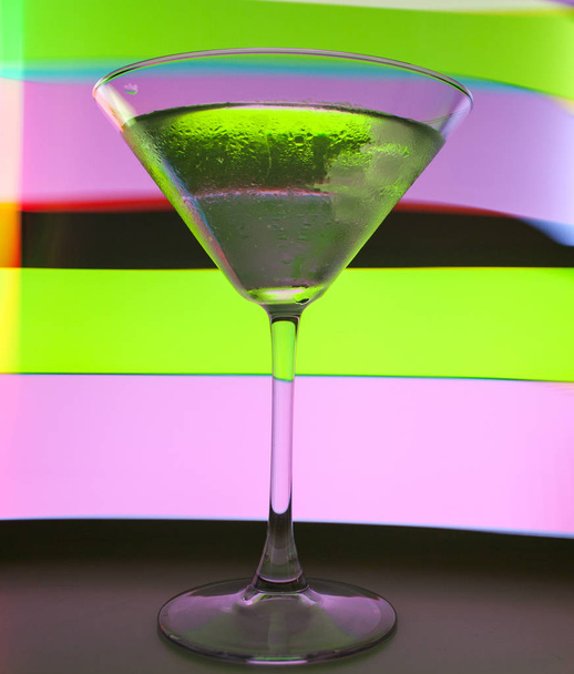 A martini glass with a cocktail in beautiful light of different colors - Φωτογραφία, εικόνα