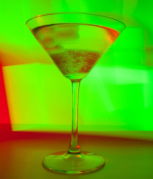 A martini glass with a cocktail in beautiful light of different colors - Foto, Imagen
