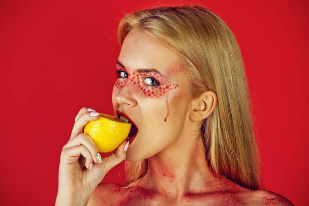woman with creative fashionable makeup bite lemon, vitamin - 写真・画像