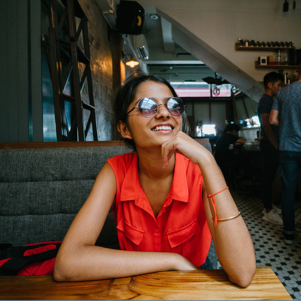 Portrait of a young and attractive Indian Asian woman smiling at the camera.  She is dressed in smart casual and is relaxed and cheerful. - Photo, image