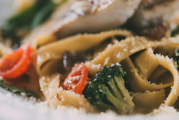 selective focus of gourmet pasta with pike perch fillet, vegetables and parmesan cheese   - Foto, Imagen