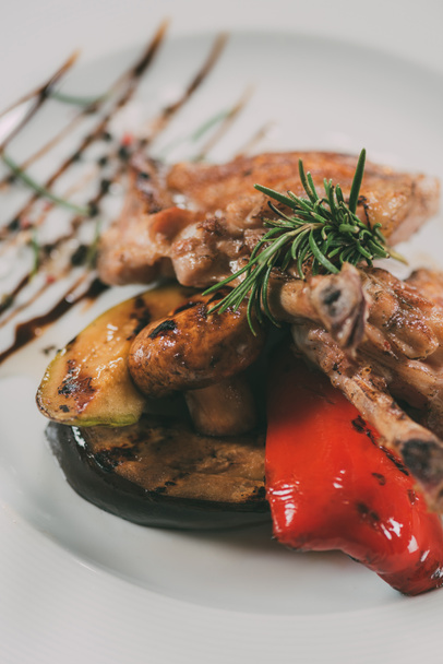 close-up view of tasty roasted chicken wings with grilled vegetables on plate  - Photo, Image