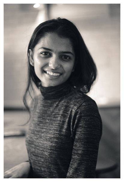 Portrait of elegant, young Indian Asian woman in a sweater in a warm, cosy cafe. She is smiling at the viewer. - Foto, Bild