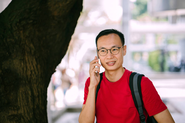 middle-aged Asian man with phone in city - Φωτογραφία, εικόνα