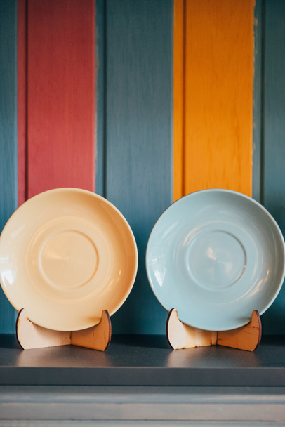 Крупный план двух декоративных пустых тарелок возле красочной стены в ресторане
  - Фото, изображение