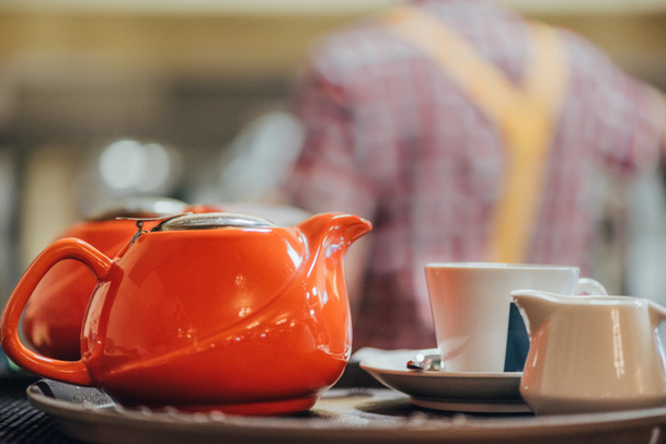 close-up view of red porcelain kettle, cup and white jug on table - Фото, зображення