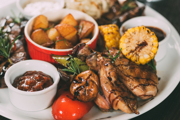tasty grilled chicken with fried potatoes, corn, mushrooms and sauce on plate  - Fotoğraf, Görsel