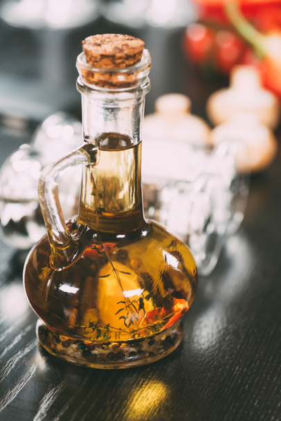 Nahaufnahme von Olivenöl mit Gewürzen in Glasflasche   - Foto, Bild