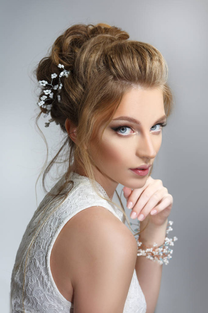 Pretty bride with beautiful elegant hairstyle, on a gray background - Valokuva, kuva