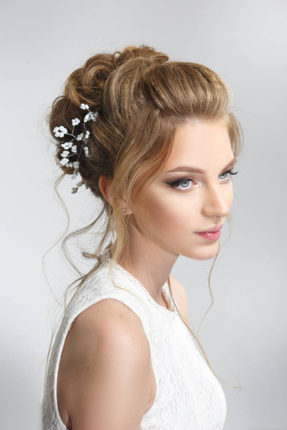 Pretty bride with beautiful elegant hairstyle, on a gray background - Фото, зображення