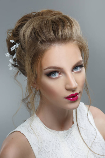 Elegant bride with a beautiful hairstyle and bright make-up on a gray background. - Φωτογραφία, εικόνα