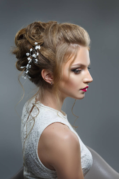 Mooie bruid met mooie elegante kapsel, op een grijze achtergrond - Foto, afbeelding