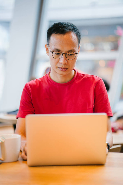 Muž středního věku asijské (čínské nebo japonské) pracovat na notebooku v kavárně. - Fotografie, Obrázek