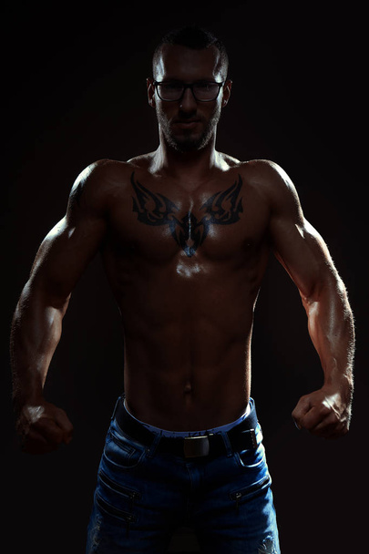 Muscular man posing in studio on dark background - 写真・画像