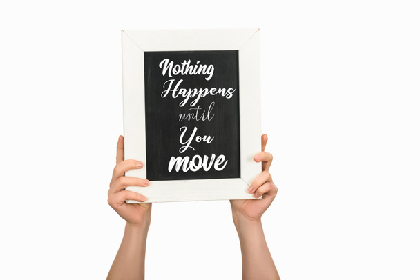 Cropped view of woman hands holding board with lettering nothing happens until you move isolated on white - Photo, Image