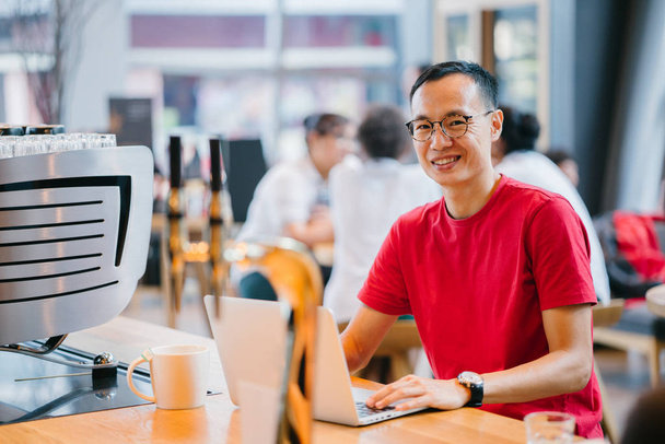 Літній чоловік азіатської (китайською або японською) робочих на ноутбуці у кафе. - Фото, зображення