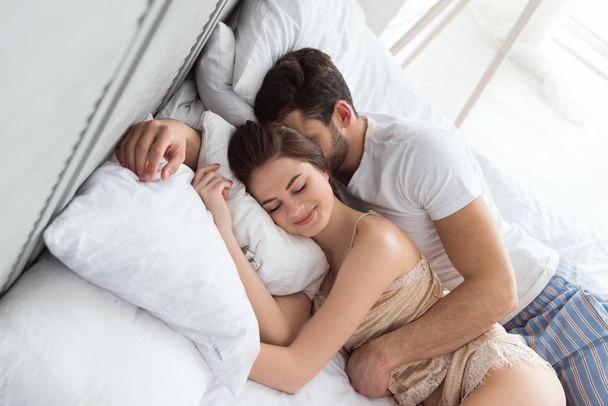 young couple in pajamas sleeping in bed together - Fotografie, Obrázek