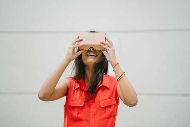 Una mujer india joven y fotogénica prueba las gafas de realidad virtual por primera vez. Ella está sonriendo y riendo en deleite y sorpresa por la experiencia
 - Foto, imagen