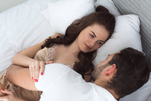 mladý pár v pyžamu ležel na posteli společně doma - Fotografie, Obrázek