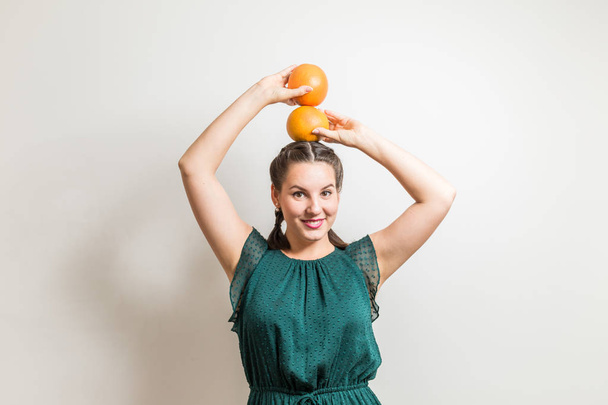 Happy laughing girl poses with a grapefruits on her head - Photo, image