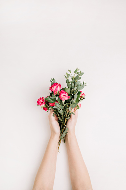 Woman hands hold rose flowers and eucalyptus branch bouquet. Flat lay, top view spring background. - Photo, Image