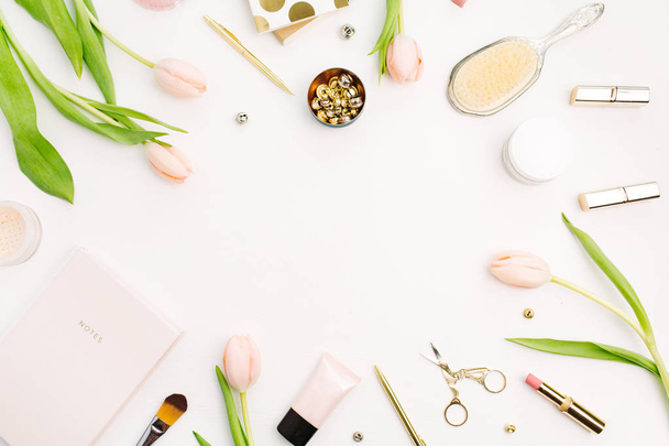 Frame of pink tulip flowers, accessories and cosmetics. Female home office desk mockup. Flatlay, top view blog hero header background. - Photo, Image