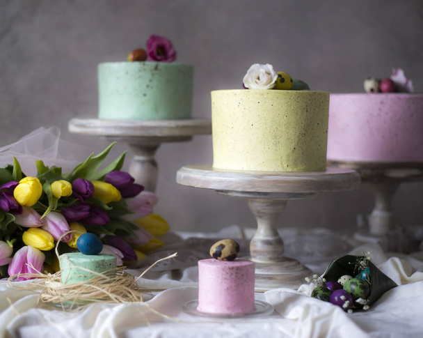 Dekoracja stołu Wielkanoc, kolorowe domowe ciasta z wiosennych kwiatów i pisanki na świątecznym stole  - Zdjęcie, obraz
