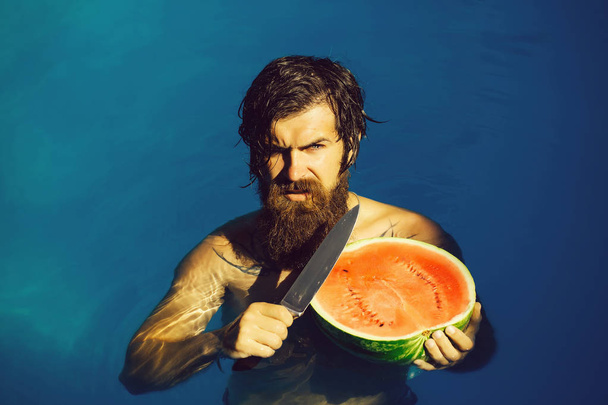 man with watermelon and knife in pool - Foto, immagini