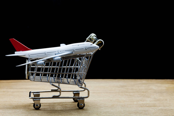 airplane model in shopping cart on wood,black background. - Photo, Image