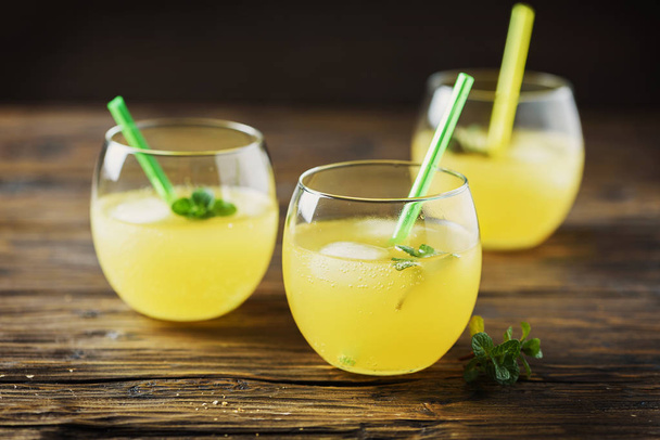 Glasses of orange cocktails with ice and mint, wooden table - Foto, immagini