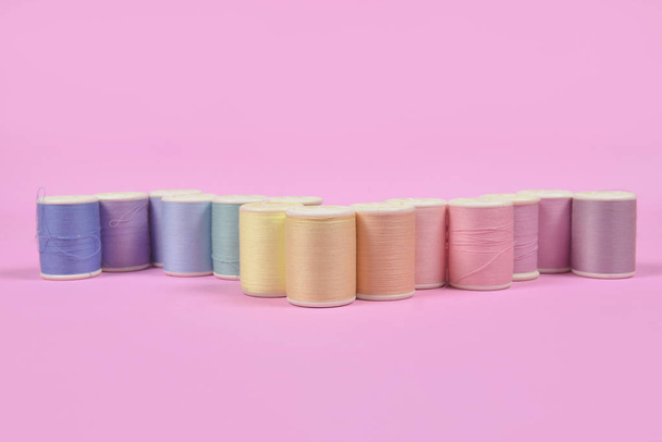 Flat lay of colored thread rolls for sewing on pink background,  - Foto, Imagem