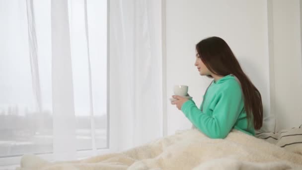 Dość młoda kobieta jest picie kawy w jej łóżku rano - Materiał filmowy, wideo