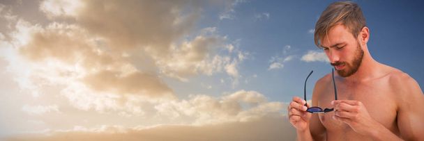 Handsome man wearing hat sunglasses against cloudy sky landscape - Valokuva, kuva