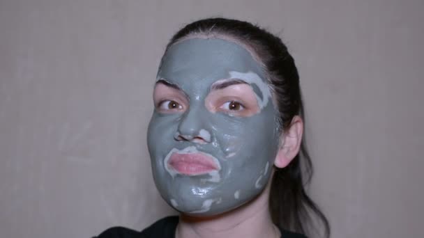 Girl with a clay mask on emotional face - Materiał filmowy, wideo