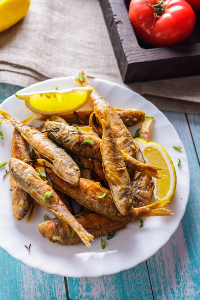 Fried mullet with lemon and herbs on a ceramic plate - Photo, Image