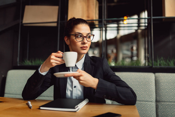 Souriant réfléchi entrepreneur féminin avec des lunettes optiques profiter du café
 - Photo, image