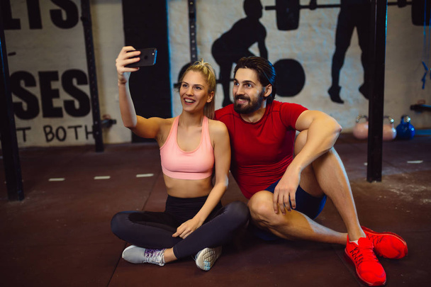 Young couple taking a selfie in gym. - 写真・画像