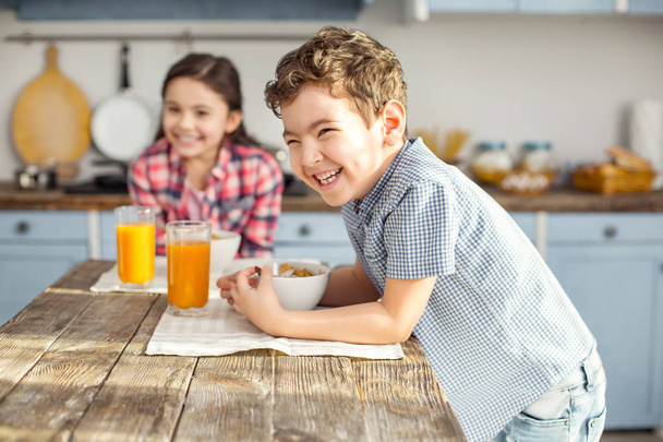Content little boy having breakfast with his sister - Фото, изображение
