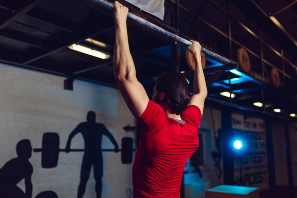 Musclé barbu mâle faire des exercices sur barre horizontale dans un club de gym
. - Photo, image