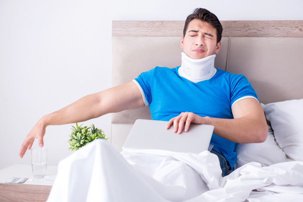Jongeman met nekletsel in bed - Foto, afbeelding