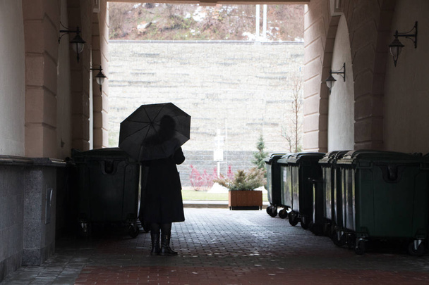 Femme sous un parapluie dans une arche sombre
 - Photo, image