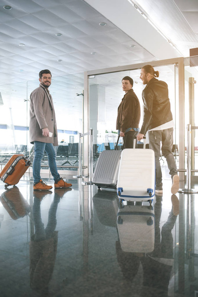 Happy friends keeping luggages in airport - 写真・画像