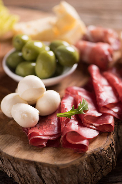 Assorted deli meats and a plate of cheese, on a wooden cutting b - Photo, Image